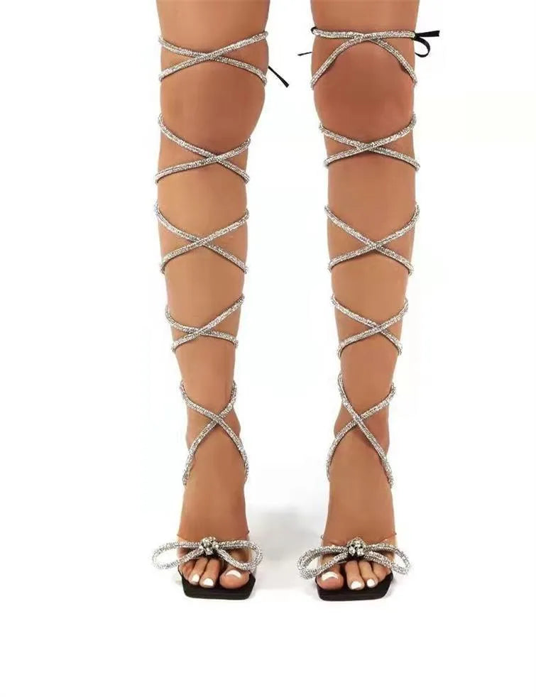 Plus size women's black strappy high-heel sandals with glittering rhinestone straps and a square toe.