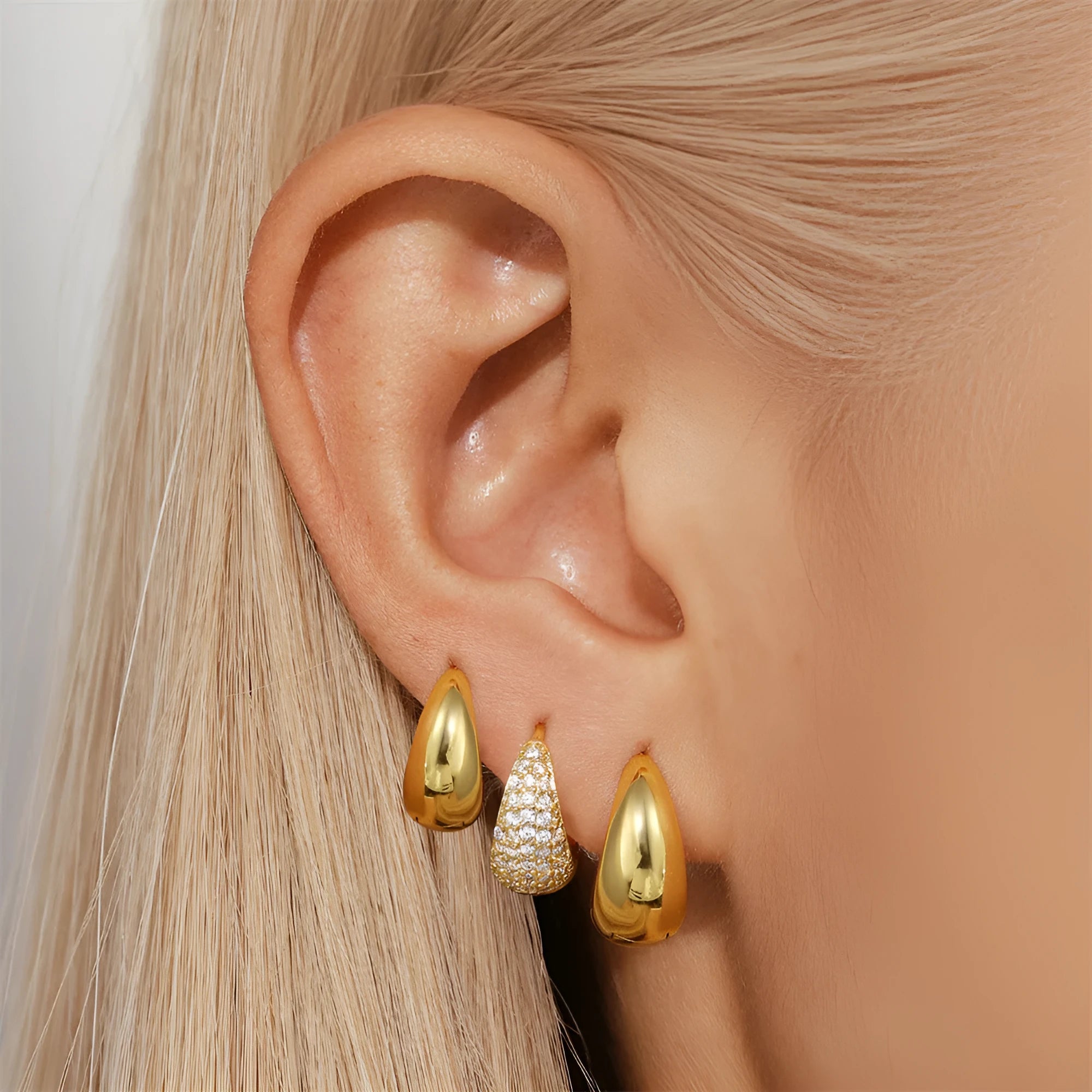 A pair of round, gold-toned brass diamond earclip earrings on a white background.