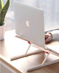 White foldable laptop bracket with heat sink base on a desk.