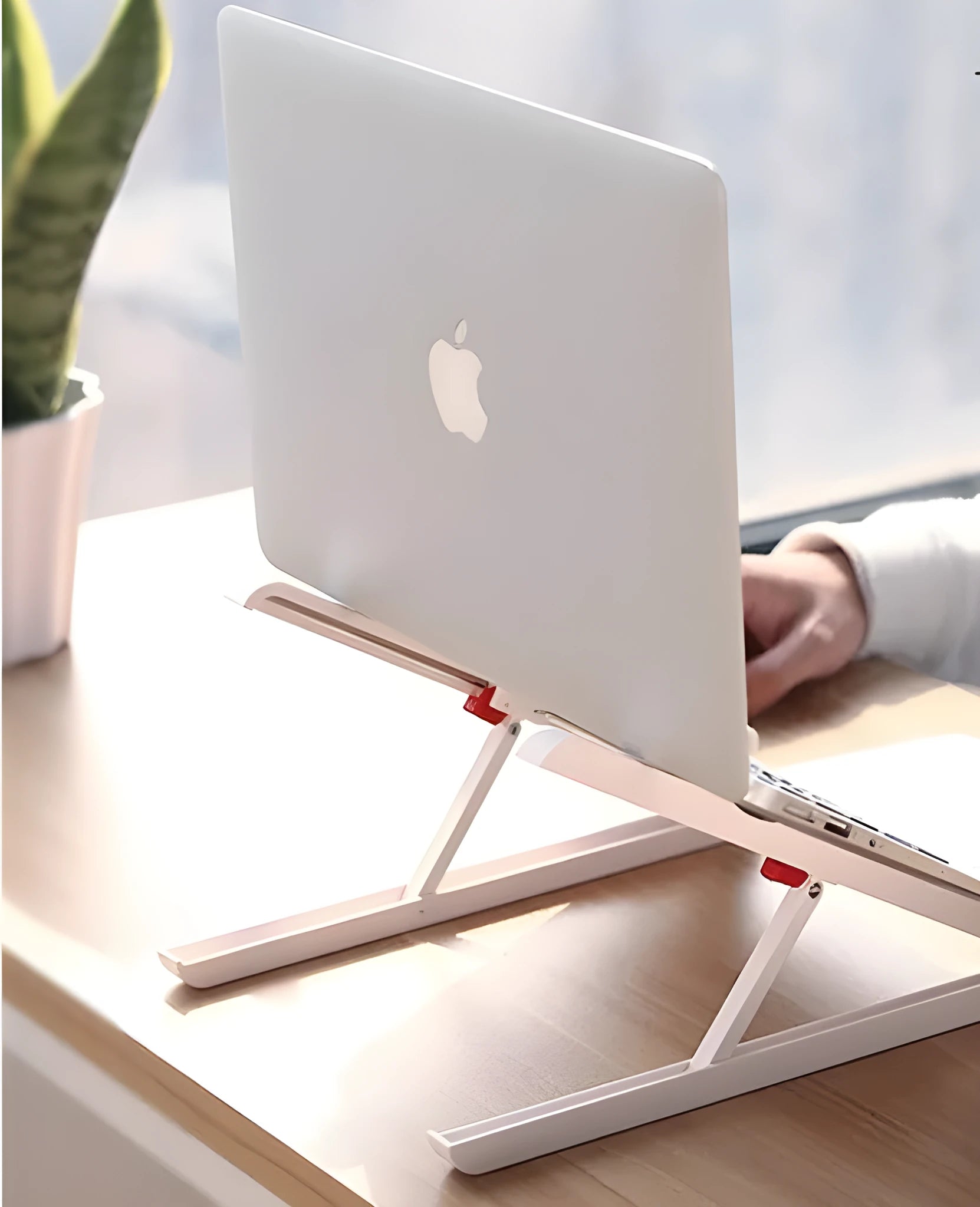 White foldable laptop bracket with heat sink base on a desk.