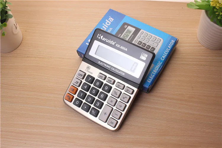 Compact silver aluminium desktop pocket calculator on a desk surface, approximate dimensions 14.5 x 11 x 2.5 cm