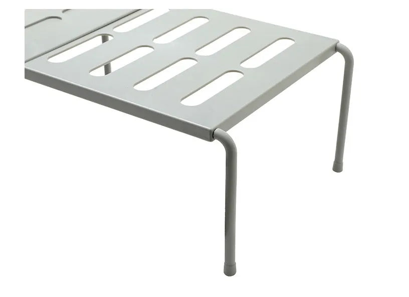White telescopic kitchen storage rack with adjustable height on a countertop