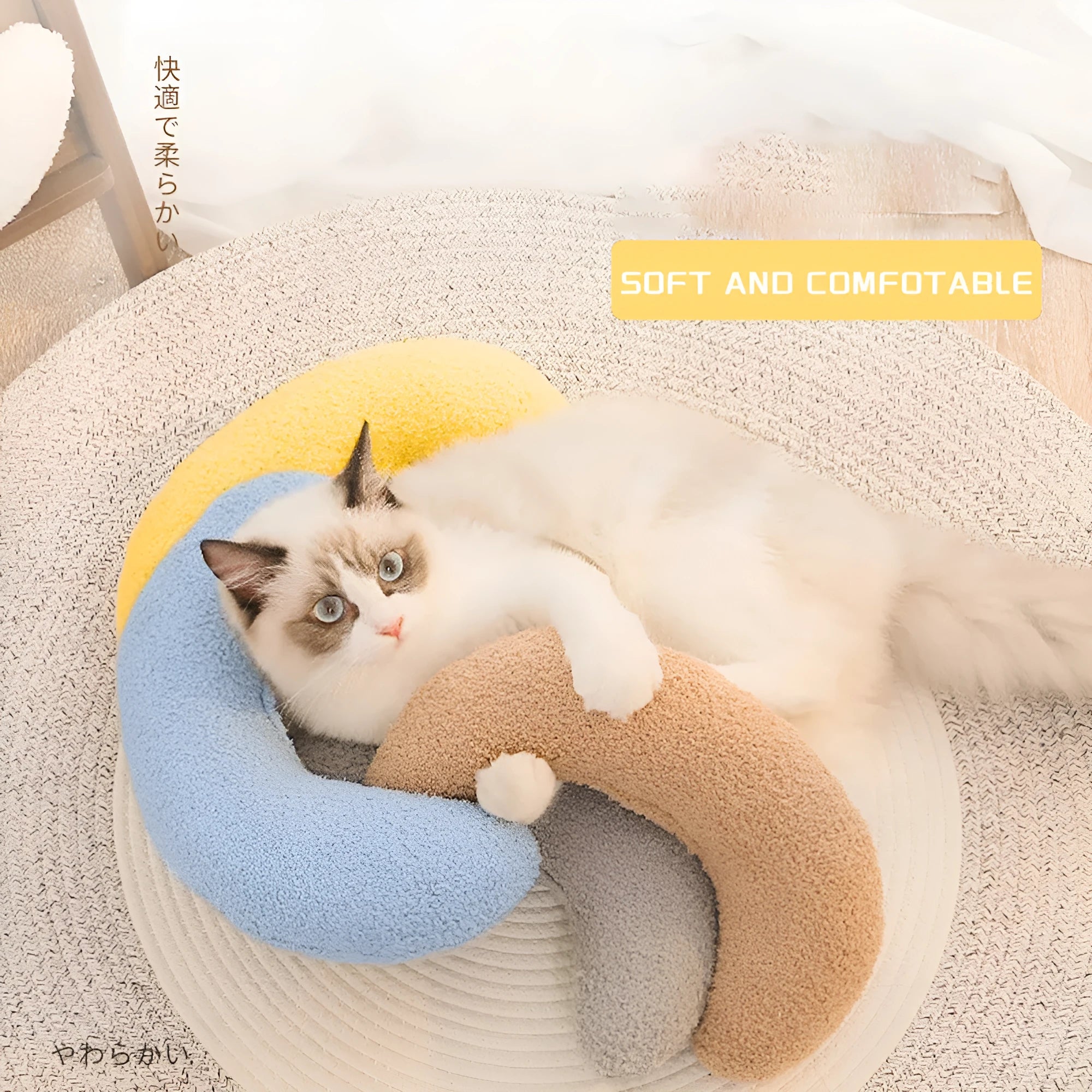 Blue U-shaped cat pillow with an adjustable fabric collar resting on a grey blanket.