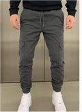 Man wearing loose-fit light blue casual trousers with patch pockets and an elasticated waistband.