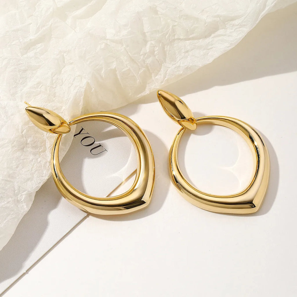 Gold electroplated copper drop earrings with tassel and love heart design on a white background