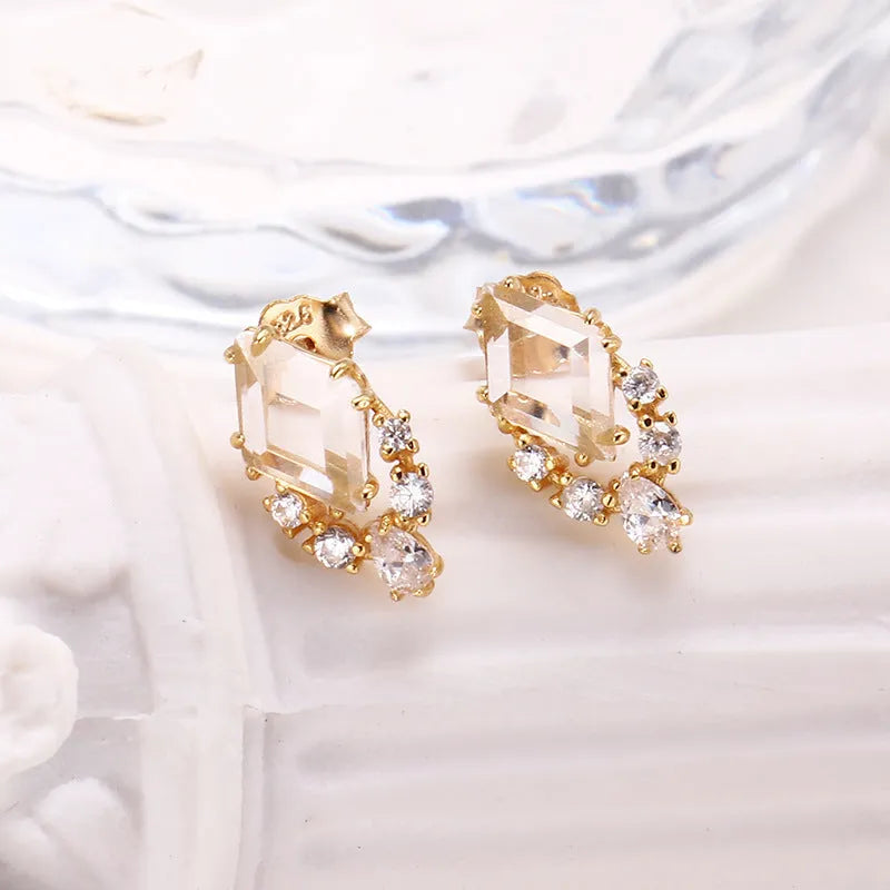 A pair of geometric sterling silver earrings with sweet white crystal studs on a white background.