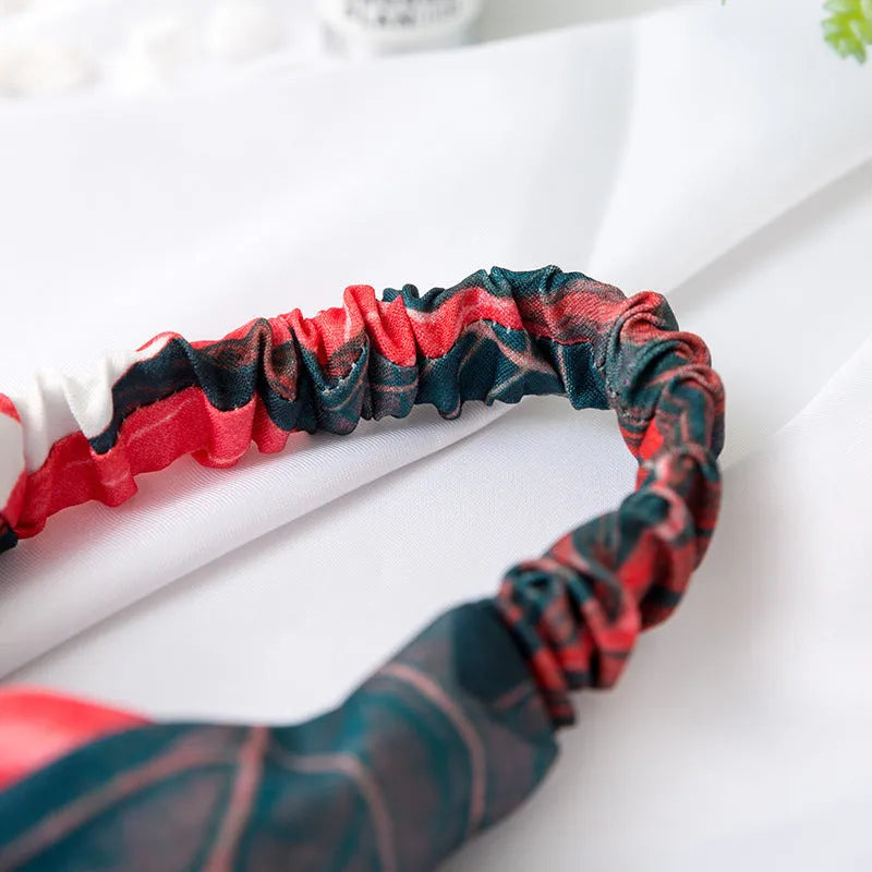 Red cloth headband with banana leaf pattern, showing wide band and elastic back.