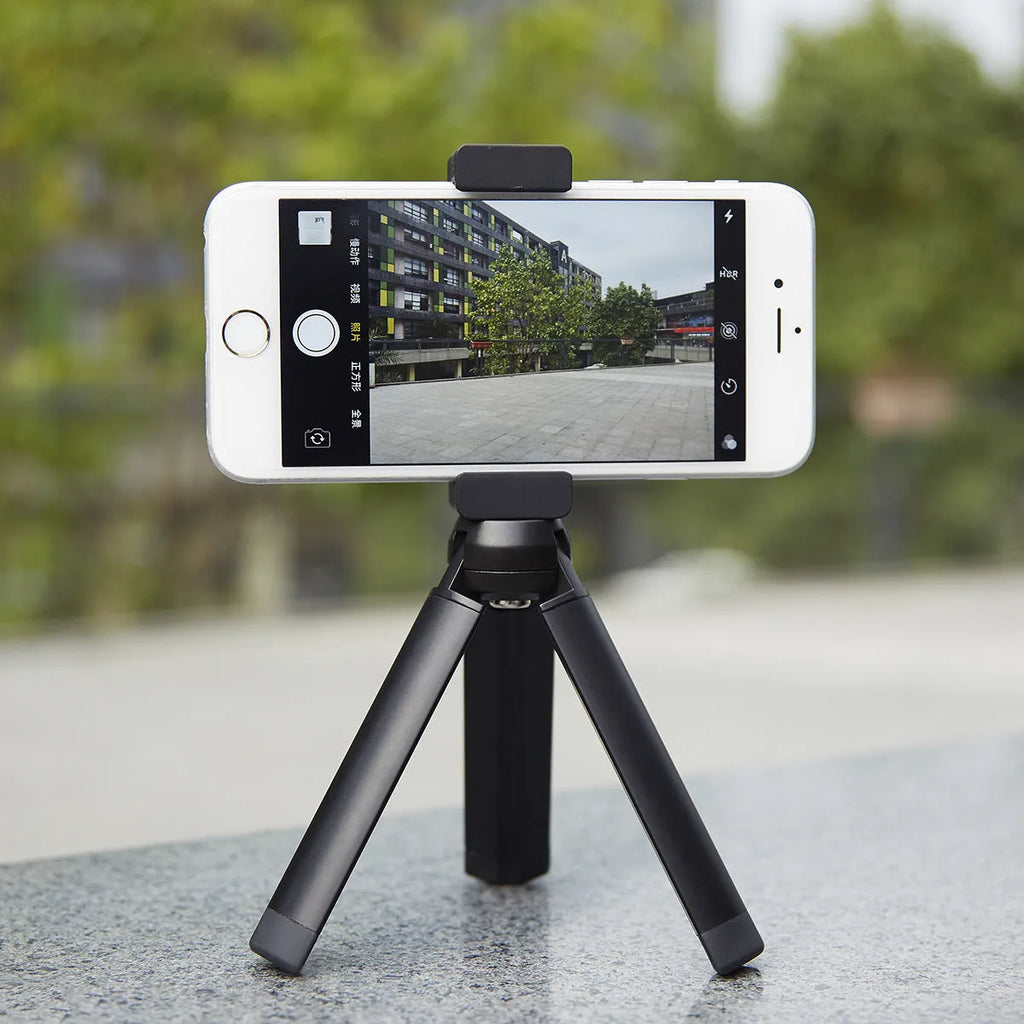 Silver aluminium alloy handheld phone mounting bracket for table top tripods, shown next to an iPhone.