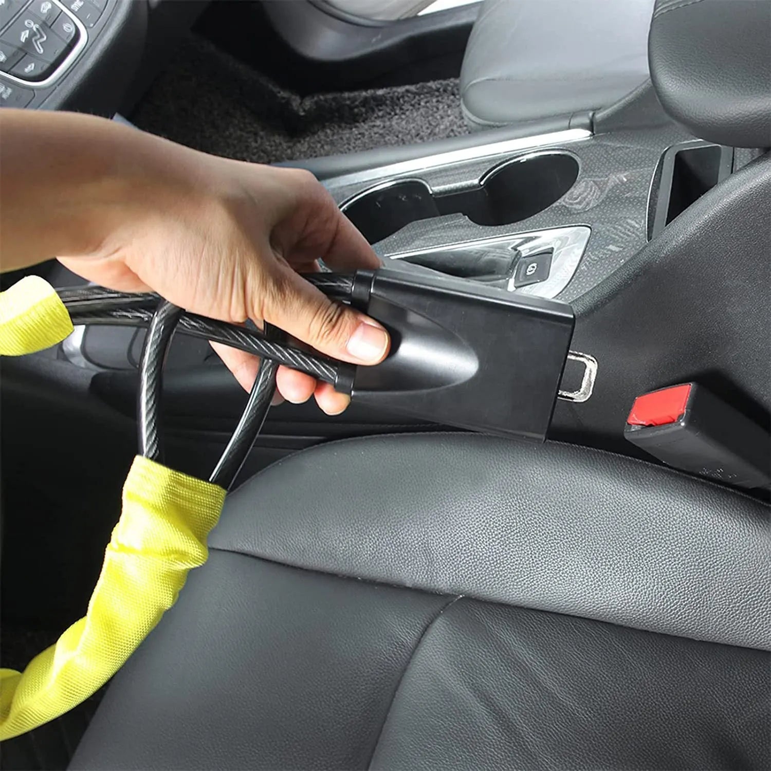 Red car steering wheel lock with steel cable secured on a steering wheel.