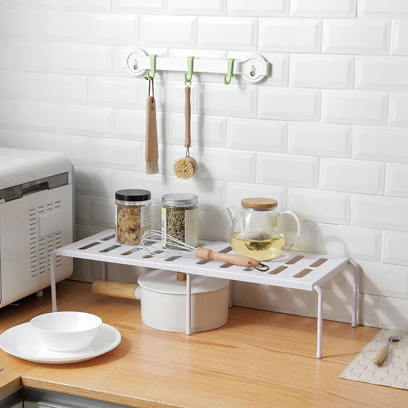 White telescopic kitchen storage rack with adjustable height on a countertop