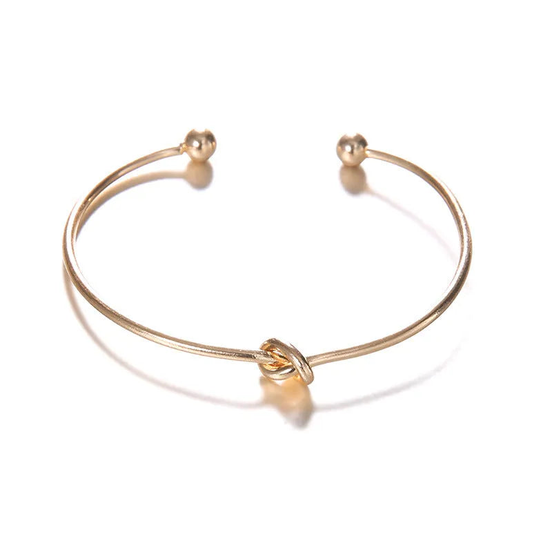 Gold women's vintage bracelet with knotted cuff design and central arrow motif