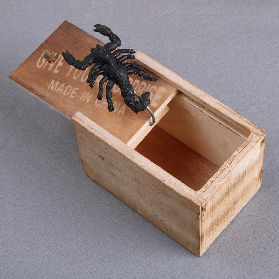 Wooden prank scare box open showing a lifelike spider figurine on a spring, next to the box lid.