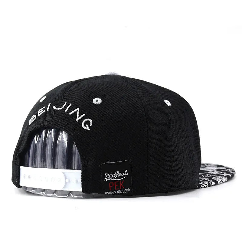 Cotton baseball cap with adjustable strap in black or white, showing embroidered letter detail on the front.