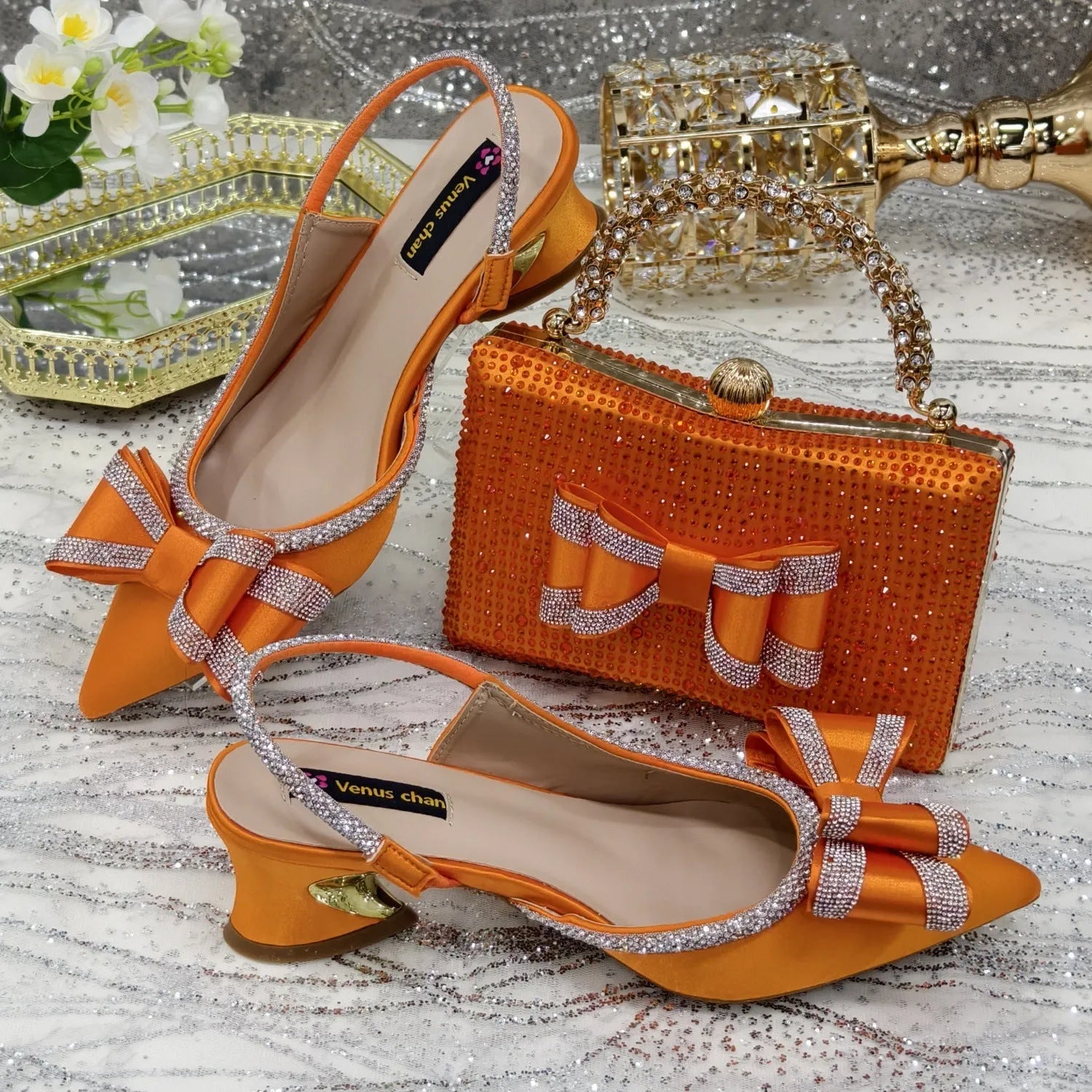 Women's pointed toe sandals with square rhinestone buckle and matching bag on a mid heel.