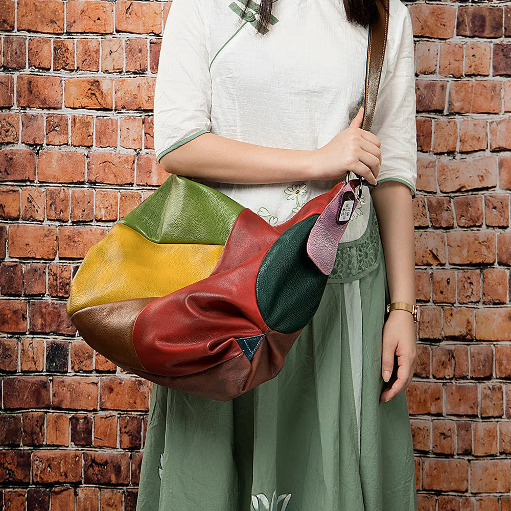 Brown cowhide leather crossbody travel bag with stitching, shown holding a laptop and A4 magazine.
