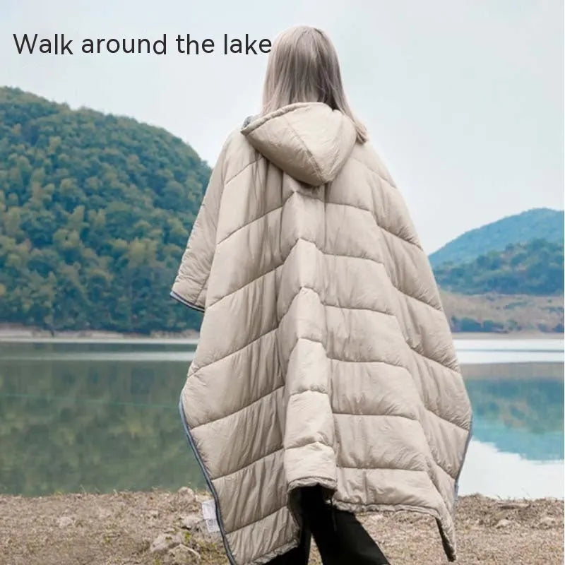 Grey outdoor cloak sleeping bag worn as a cape, showing its large 200x140cm size and hooded design.