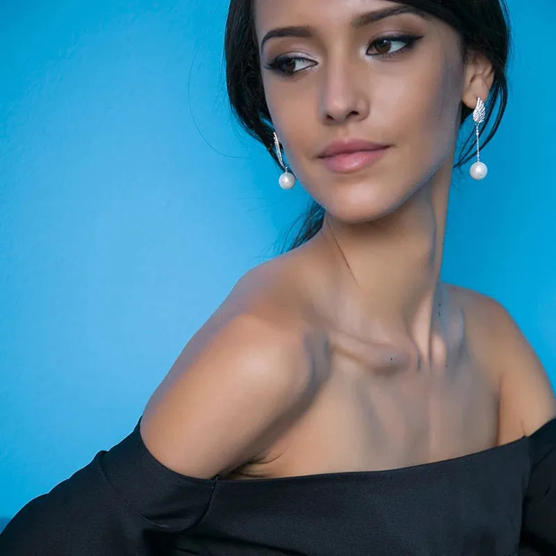 A pair of silver angel wing earrings with diamond treatment and gold-plated gemstone inlays on a platinum-colour finish.