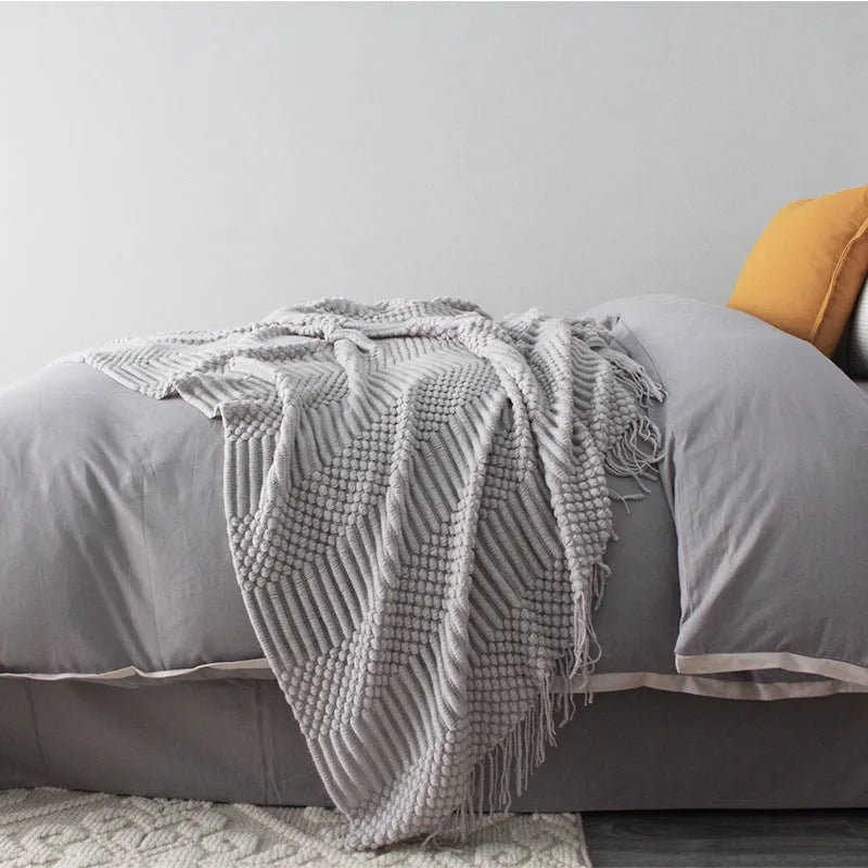Small grey polyester nap blanket folded on a sofa, showing its 127x170cm size.