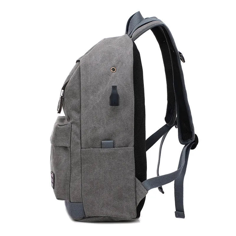 Canvas backpack in grey colour showing external USB port and multiple compartments.