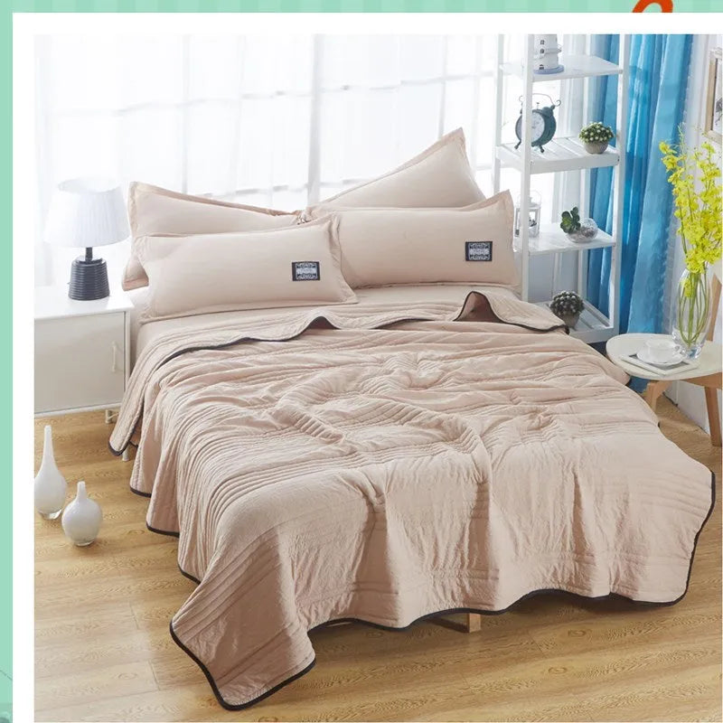 Plain colour seersucker summer cooling quilt shown in light pink on a bed.