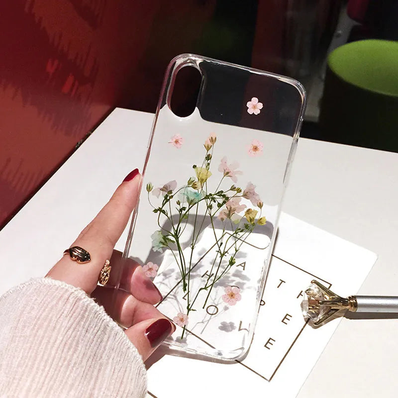 Clear soft TPU iPhone case with pink dried flowers preserved in epoxy resin on the back.