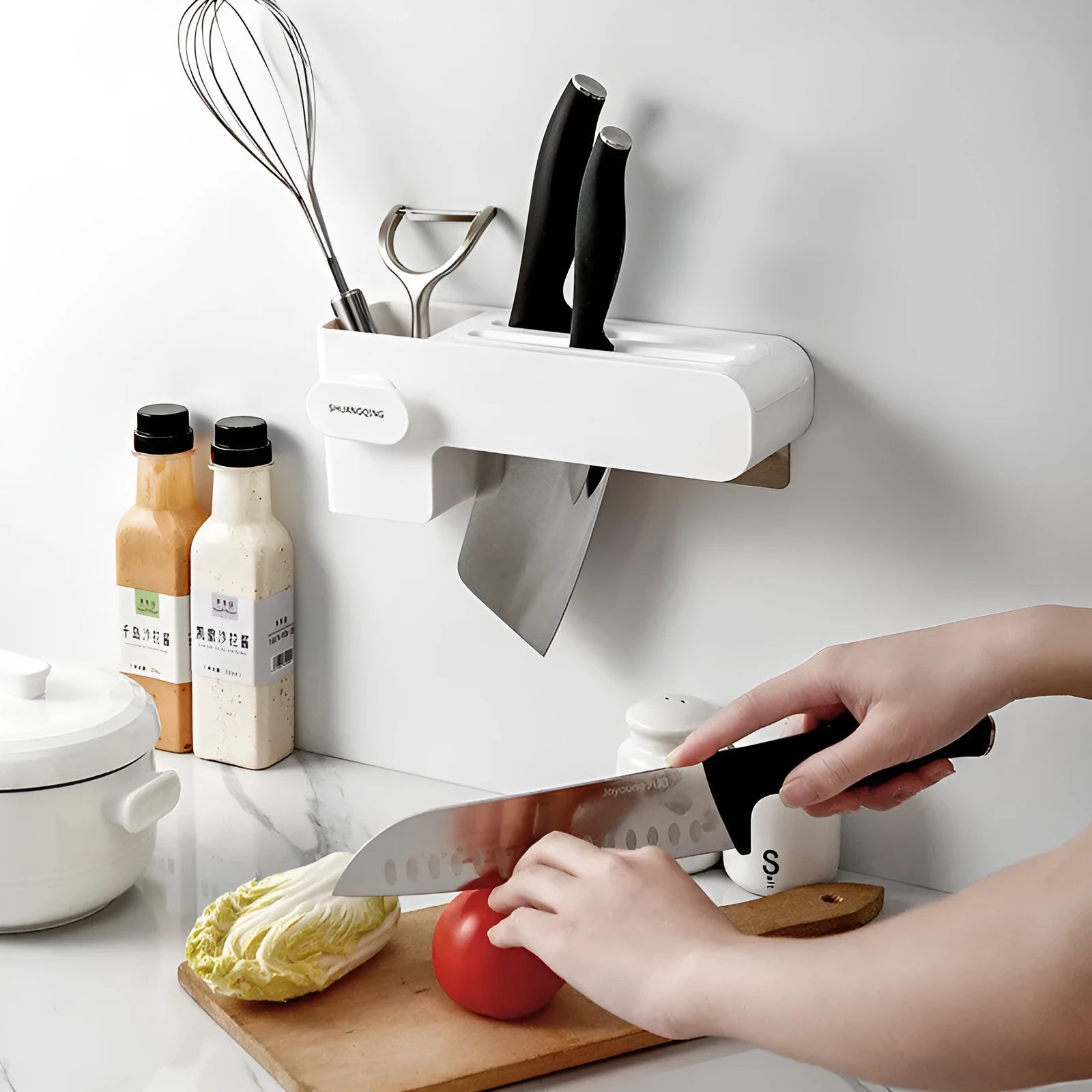 White plastic wall-mounted magnetic knife rack holding several kitchen knives