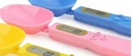White electronic digital spoon scale with LCD display on a kitchen counter.