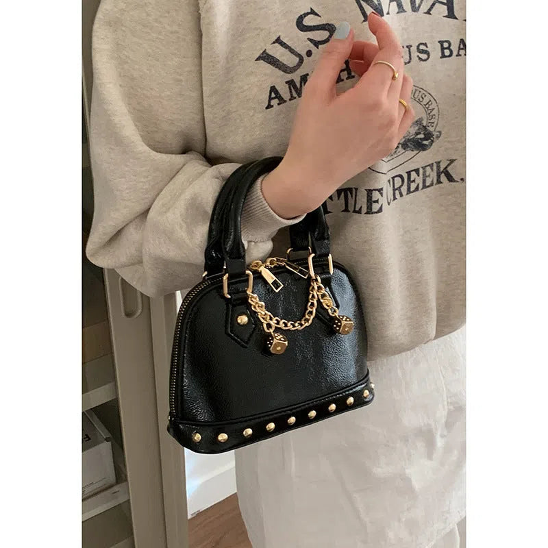 Champagne-gold PU shell bag with stitched seams, worn as a shoulder bag against a neutral background