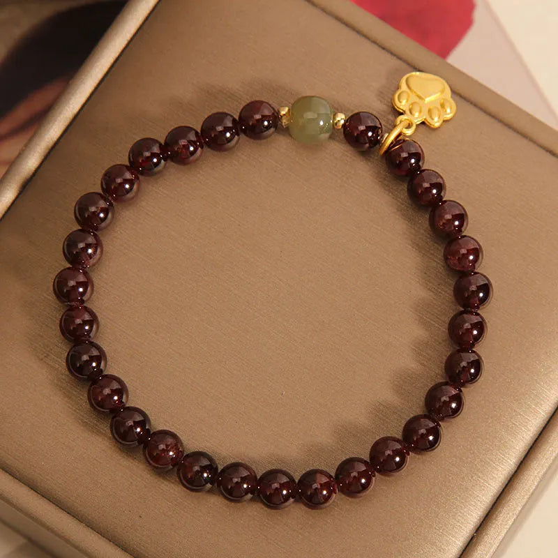 Women's crystal bracelet with a cat's paw garnet design on a polished metal setting.