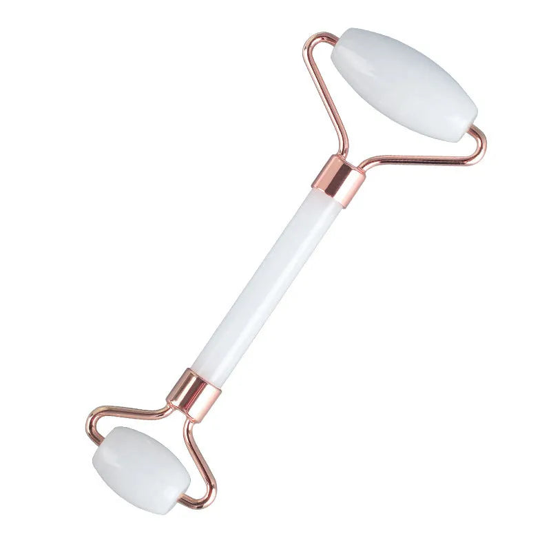 White jade double-headed facial roller and scraping board set on a flat surface.