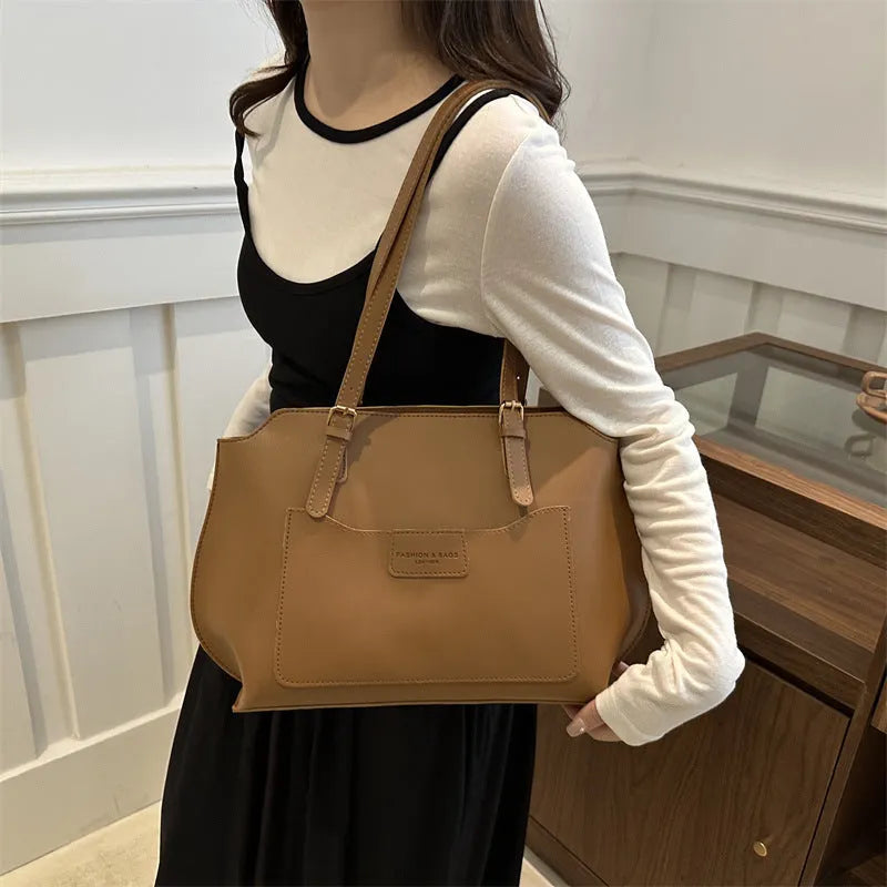Women's black PU tote bag with shoulder straps showing internal mobile phone pocket