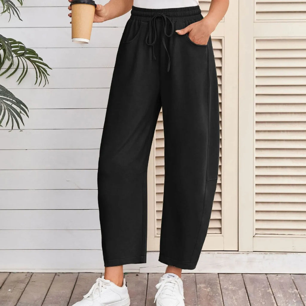 Women's loose cropped sweatpants in apricot colour with drawstring waist and side pockets on a neutral background.