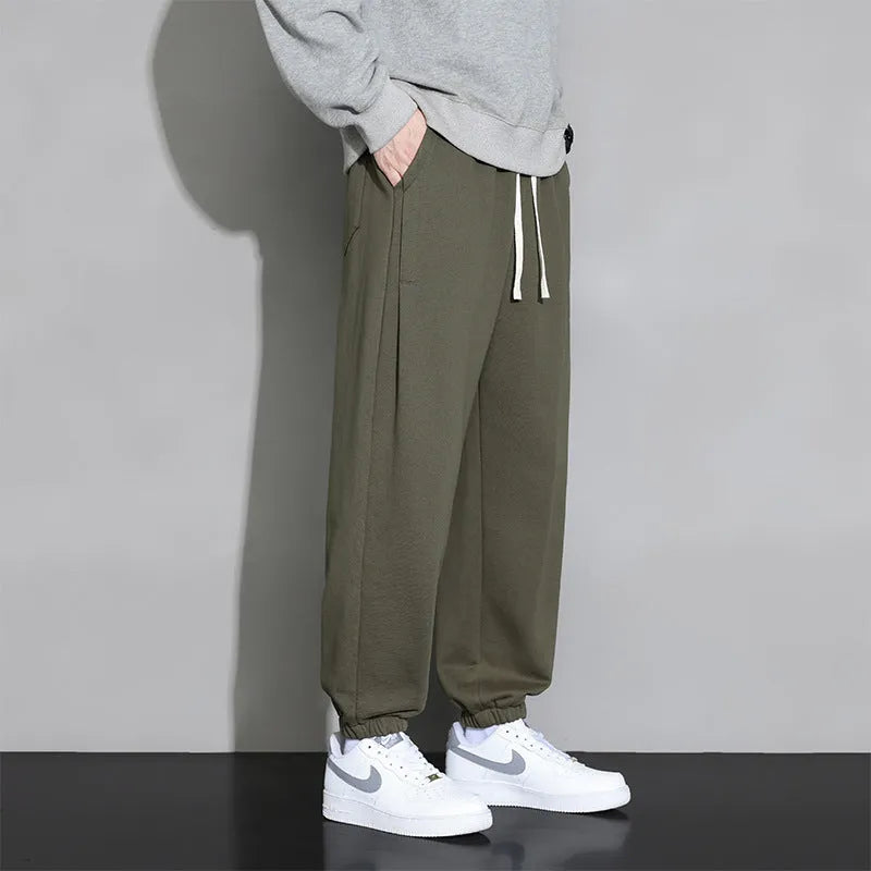 Men's loose grey casual sports trousers with drawstring waist on a plain background