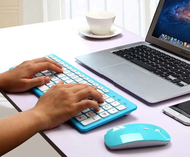 Black, white, pink, and blue wireless keyboard and mouse set with a micro USB receiver on a desk.