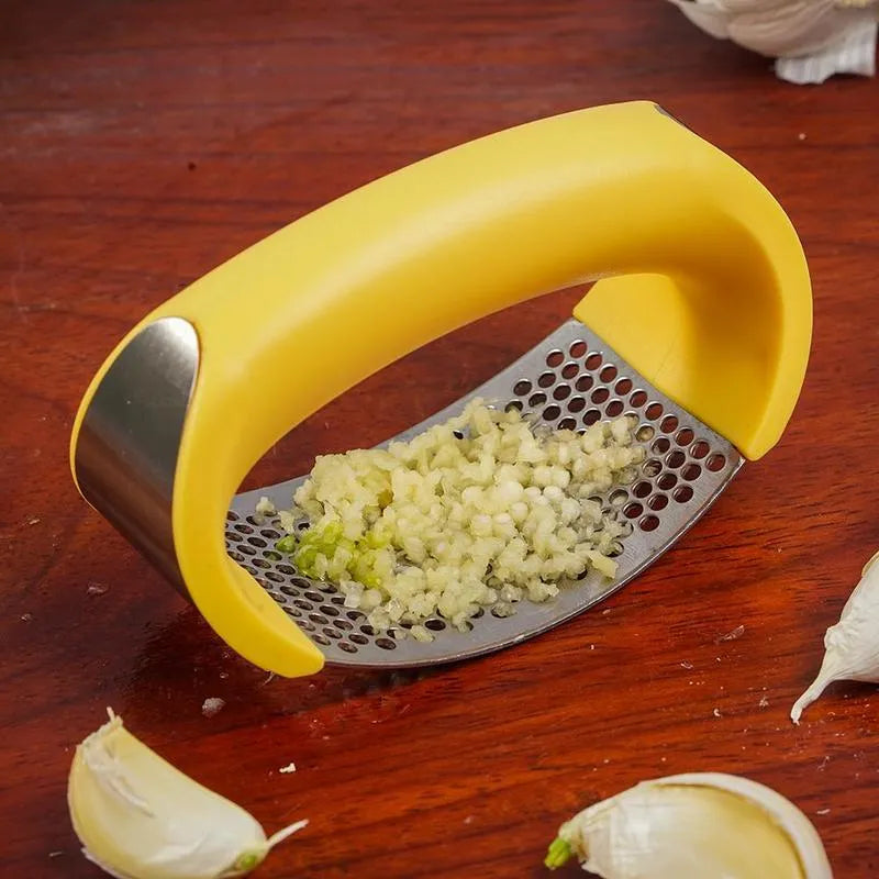 Stainless steel garlic press with ergonomic black handle on a kitchen counter.