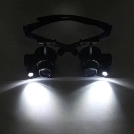 Black hands-free LED magnifying glasses with interchangeable lenses on a headband for watch repair.