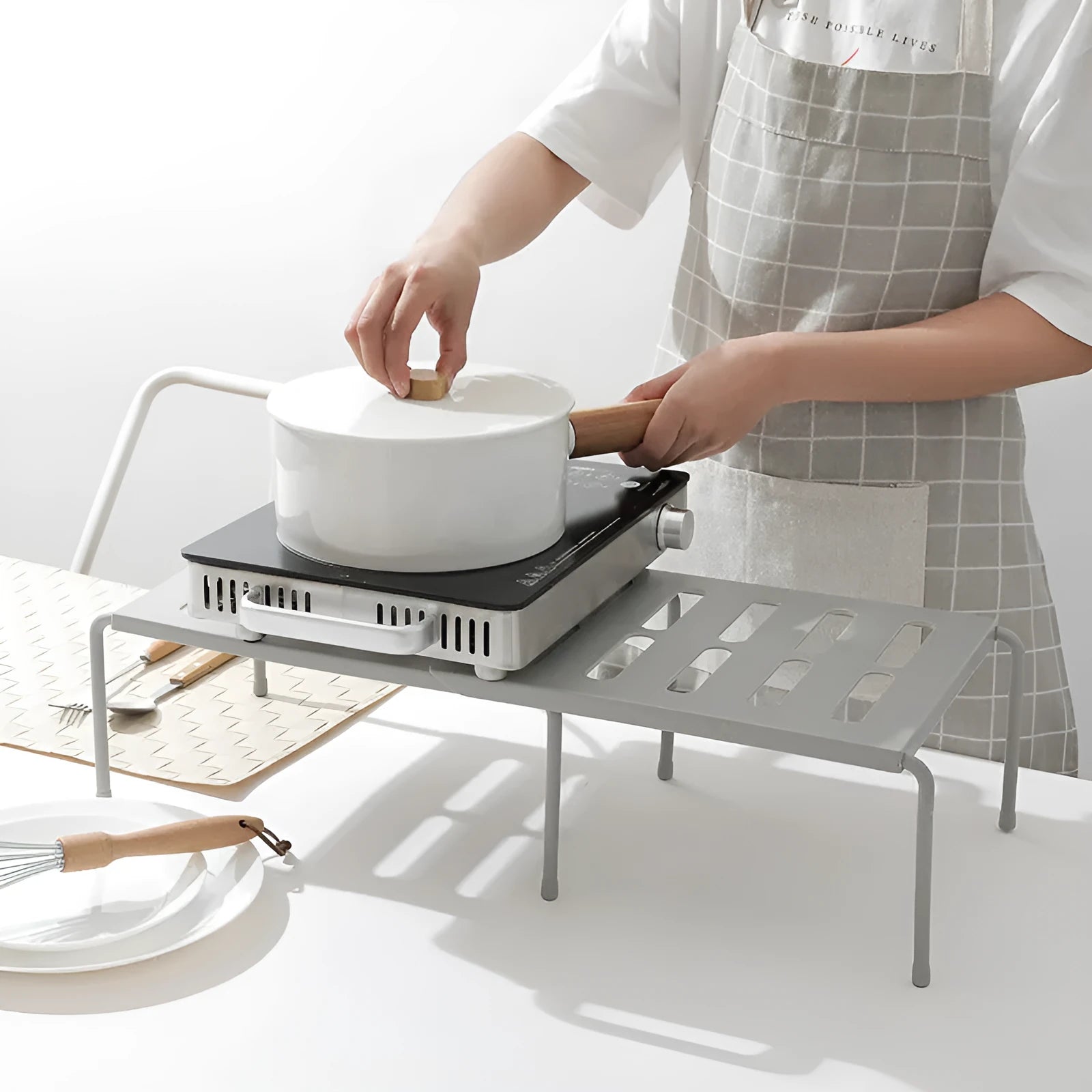 White telescopic kitchen storage rack with adjustable height on a countertop