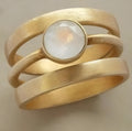 Gold geometric titanium steel ring with a small white chalcedony stone set in a hollow design.