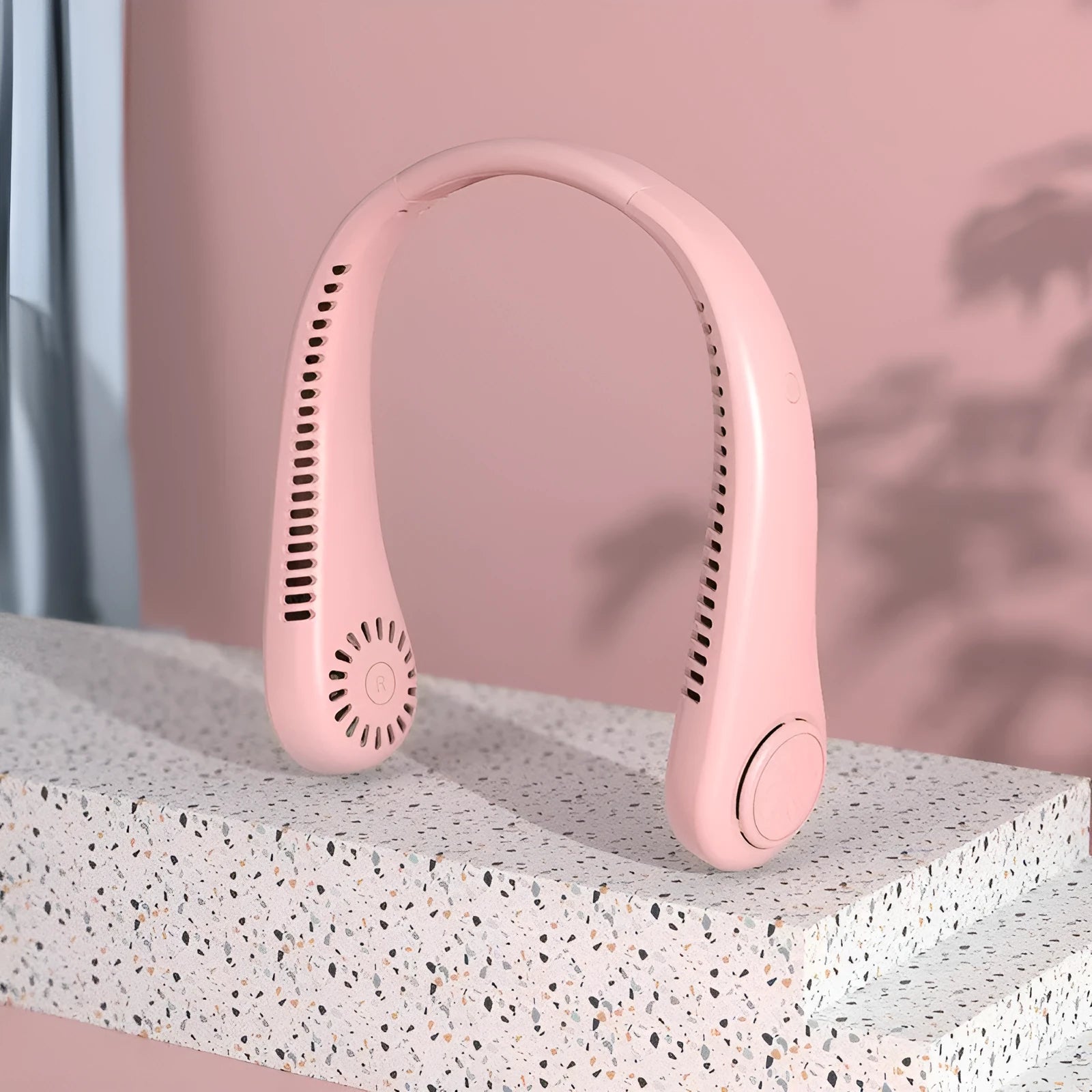 Pink bladeless neck fan being worn, showing USB charging port and control buttons.