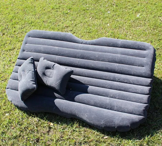 Universal inflatable car bed with flocked surface, shown with two pillows inside a vehicle.