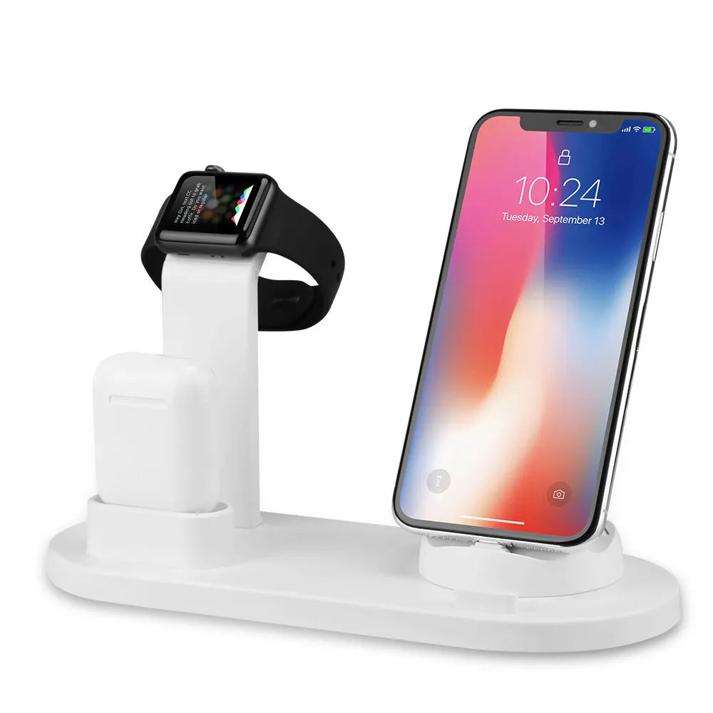 White headphone charging stand with dual USB ports on a wooden desk next to wireless headphones.
