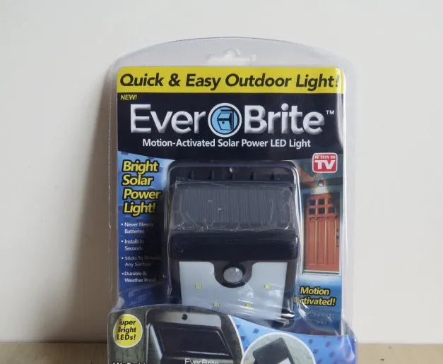 Silver outdoor solar-powered LED sensor light mounted on a wall with four illuminated bulbs.