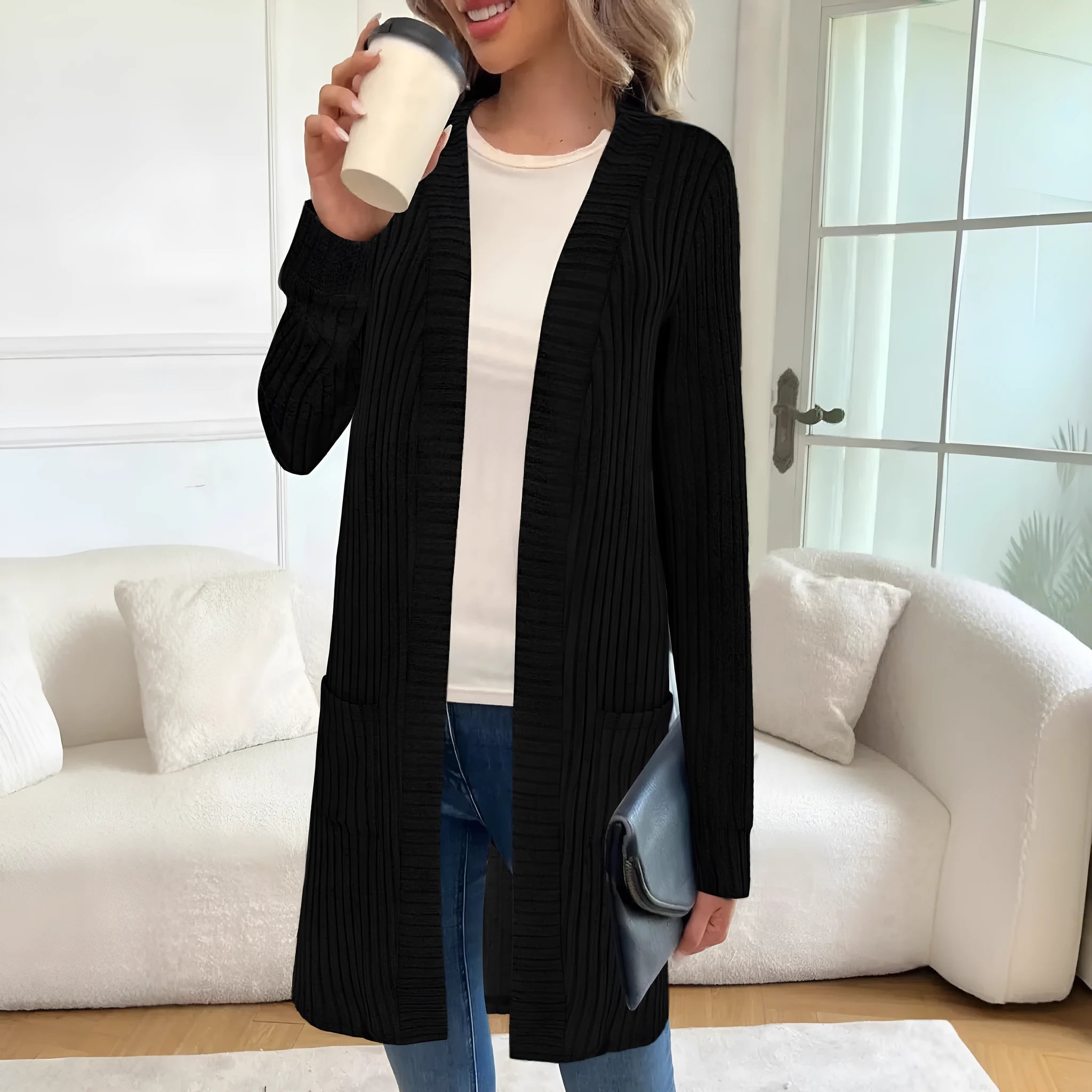 A woman wearing a loose grey knitted cardigan jacket with long sleeves and patch pockets.