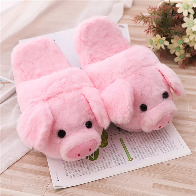 Pink pig-shaped plush floor slippers on a white background.