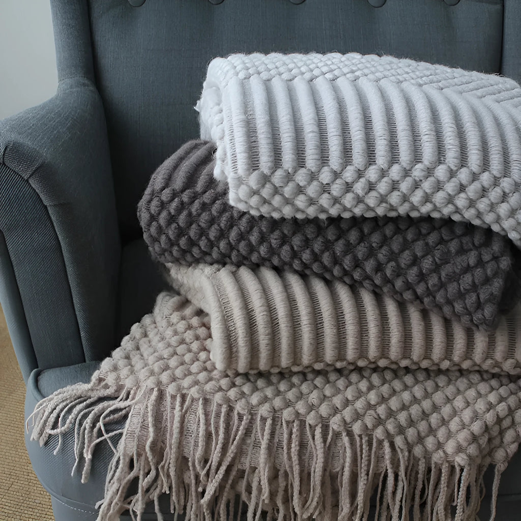 Small grey polyester nap blanket folded on a sofa, showing its 127x170cm size.