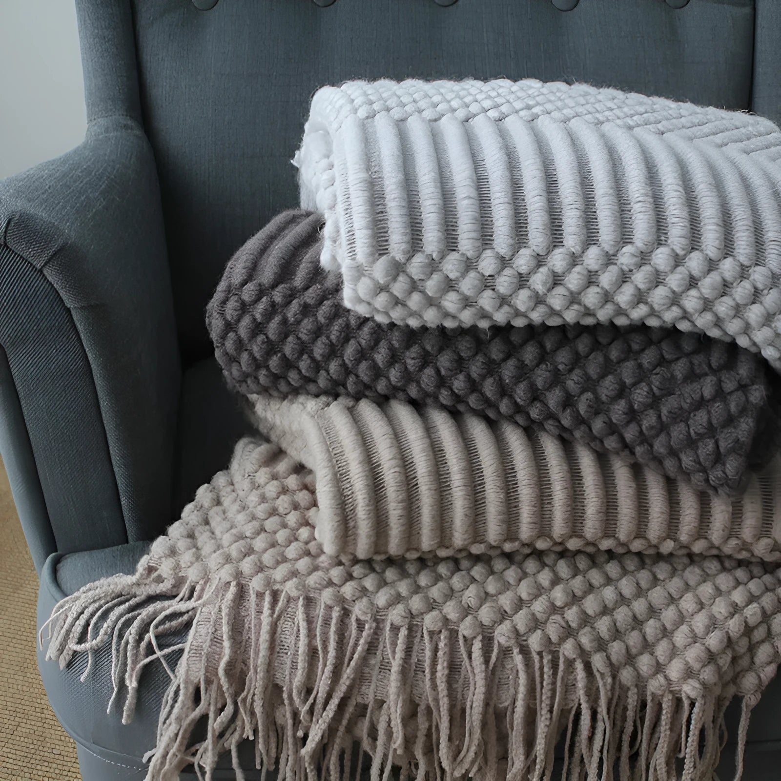 Small grey polyester nap blanket folded on a sofa, showing its 127x170cm size.