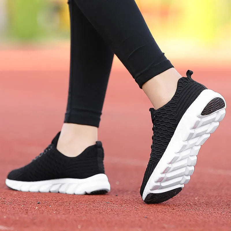 Women's running shoes in black, pink, or white with a fly weave upper and durable outsole.