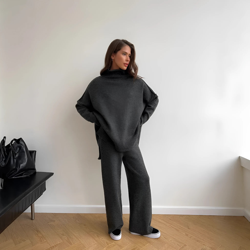Women's dark grey acrylic knit sweater suit with side-slit top and matching trousers.