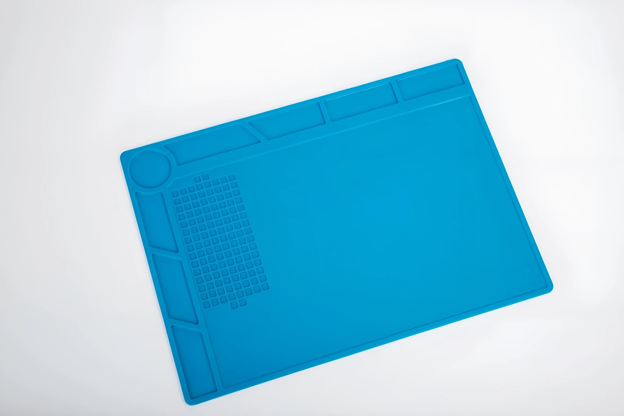 Blue silicone watch repair table mat with a non-slip surface for securing small components.