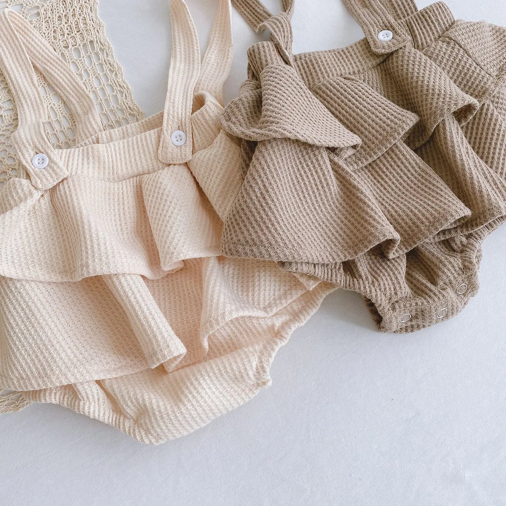 Baby girl wearing a cotton romper with a pleated lotus leaf sling and triangle climb design in apricot colour.